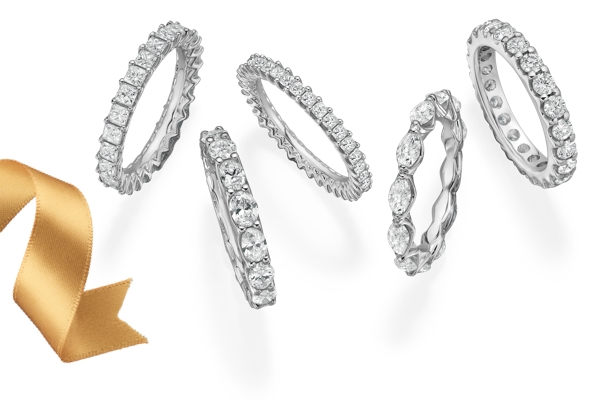 Five diamond eternity bands with princess, round, marquise, emerald and cushion cut diamonds set in white gold on a white background and a gold ribbon.