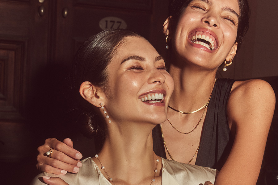 Image of two women hugging wearing an assortment of fine jewelry.