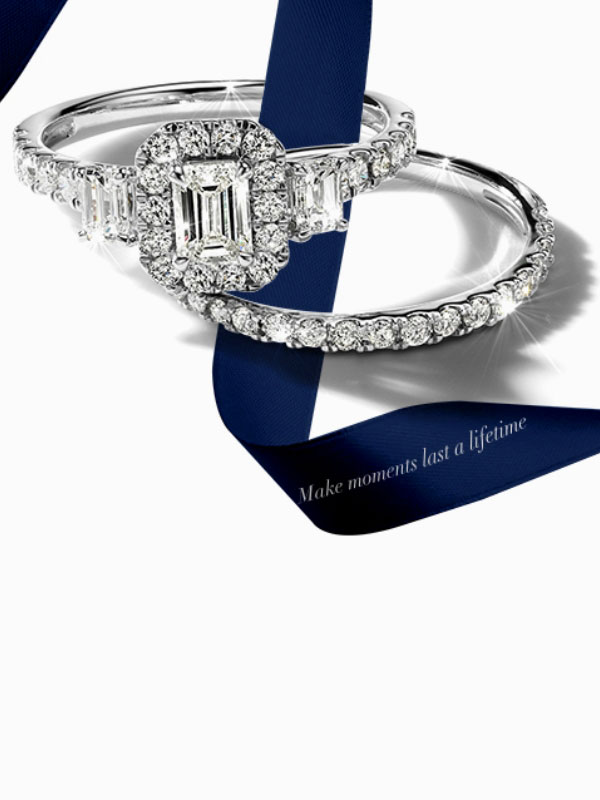 Brilliant Moments engagement ring and wedding band on a blue ribbon. Shop all Brilliant Moments 14K Gold and Diamond jewelry.