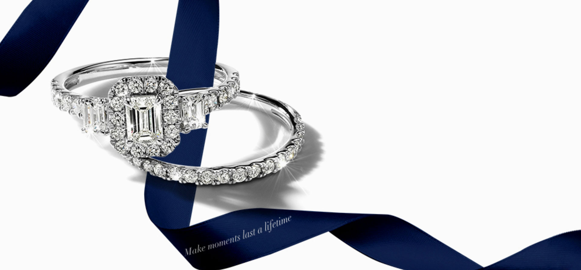 Brilliant Moments engagement ring and wedding band on a blue ribbon. Shop all Brilliant Moments 14K Gold and Diamond jewelry.