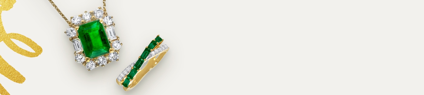 A May birthstone in one ring and one necklace against an off-white background.