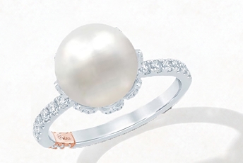 White gold engagement ring with diamonds on the band and large, single pearl in the center