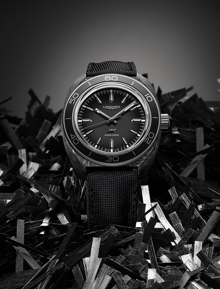 Longines Heritage watch with round black dial, red bezel markers and stainless steel bracelet.