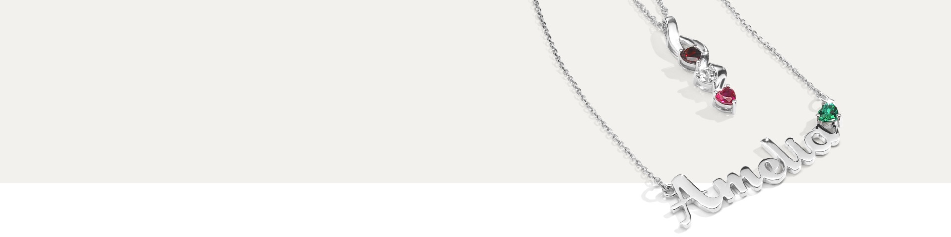 Two personalized birthstone necklaces from Jared on a light grey background.
