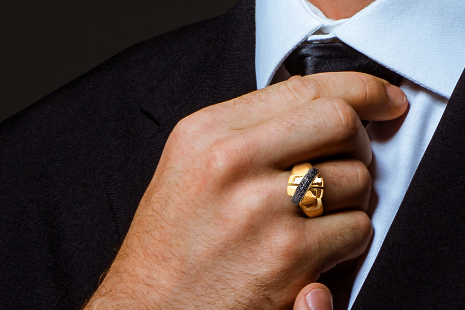 Man's hand wearing a yellow gold ring with black diamonds from Y Knot Collection