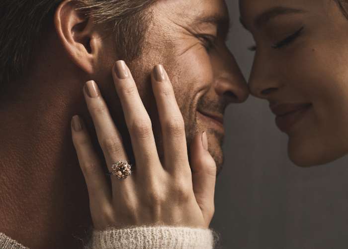 Man and woman embracing featuring engagement ring