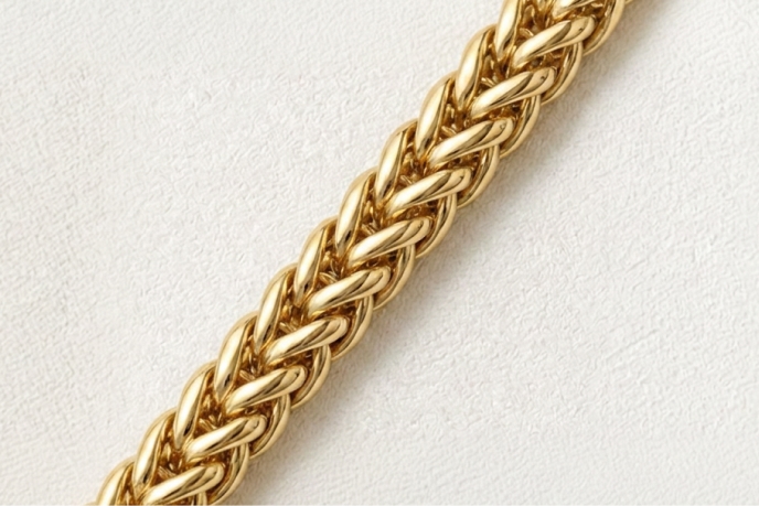A gold wheat necklace against a white background