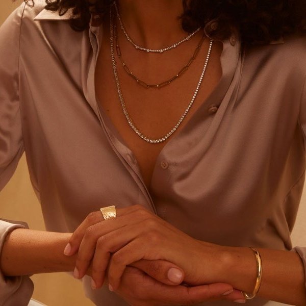  Woman wearing gold and diamond necklaces layered in different lengths