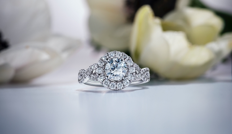 Round cut white gold diamond ring with pave halo on a tabletop