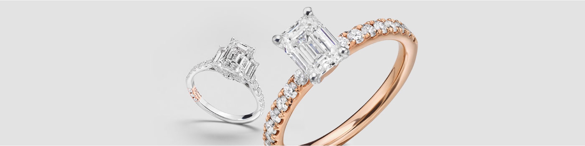 Close up shot of white gold and rose gold engagement rings with Emerald-cut center diamonds.