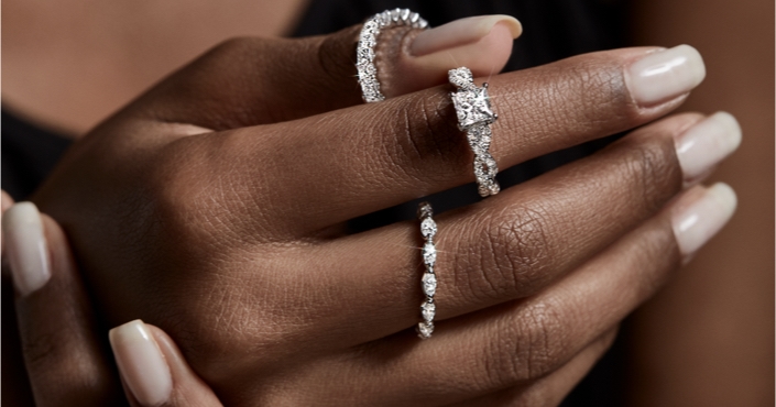 Image of woman's hand wearing and holding diamond rings.