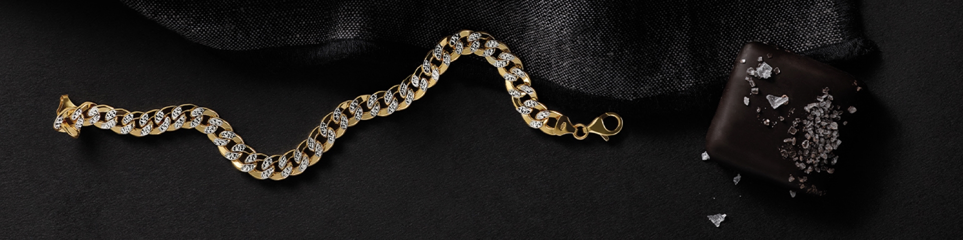 Men's yellow gold link chain bracelet with diamonds on a black textured background
