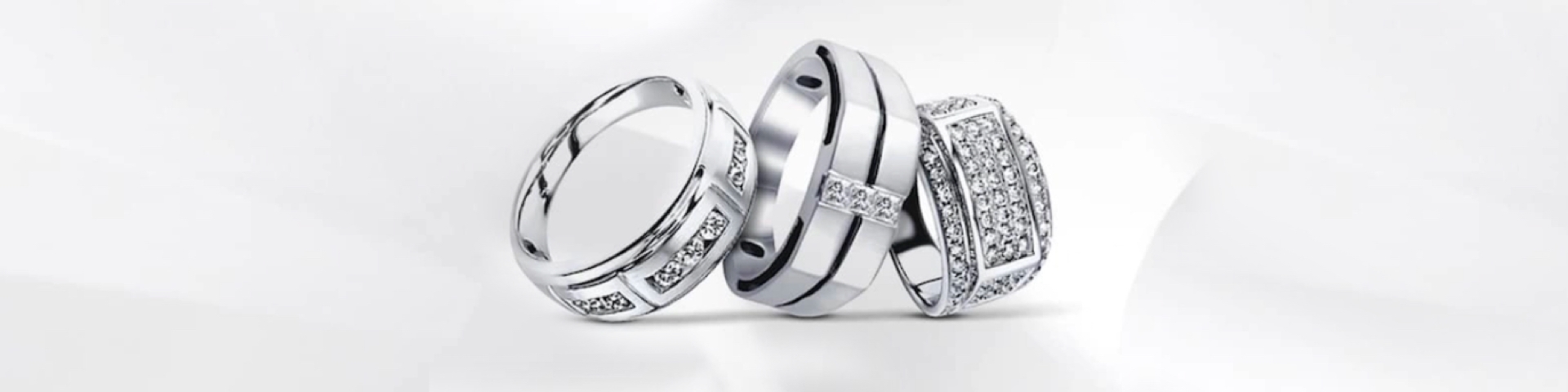 Three men's white gold rings on a grey background