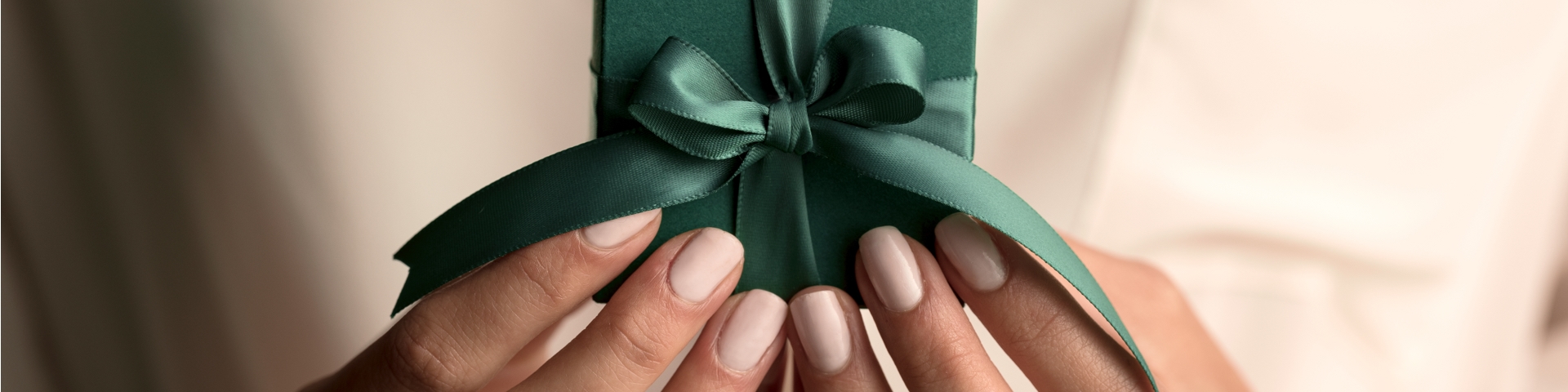 Woman holding a green gift box with green ribbon and bow in her hands