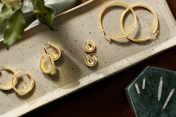 Image of gold hoop earrings laying in a jewelry box and jewelry dish.