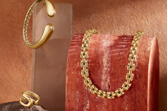 Image of bold gold looks featuring a ring, chain, and bracelet.