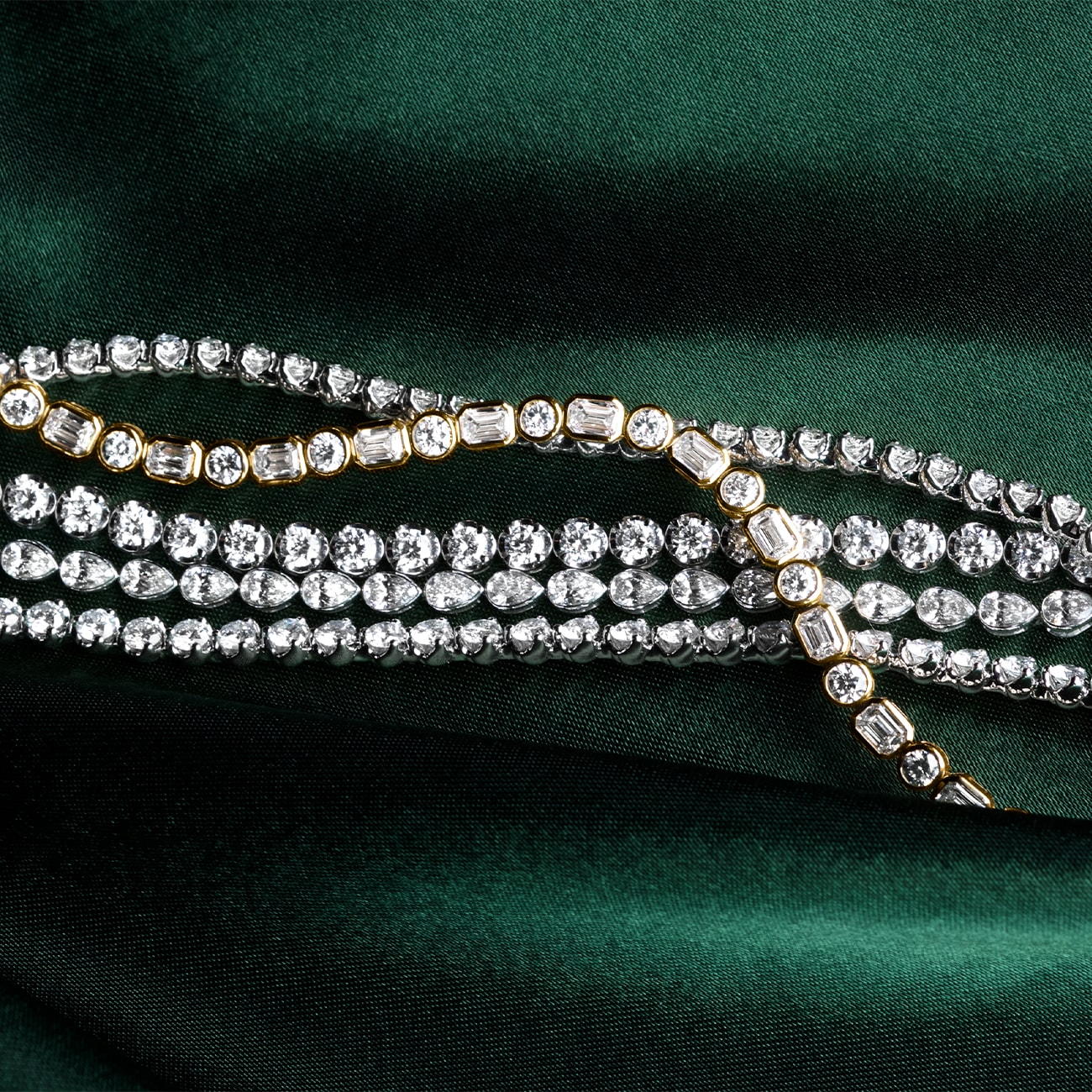 Multiple diamond bracelets on a dark green background