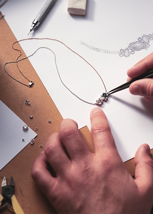 Hands designing an engagement ring on paper