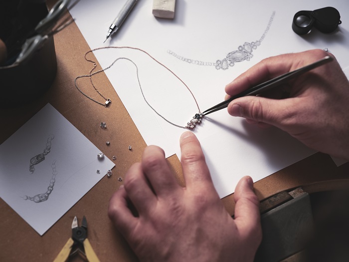 Hands designing an engagement ring on paper